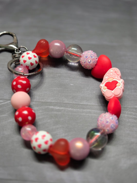 Valentine's Day - Wristlet - feat Gnome Holding a Large Red Heart with a Multitude of Various Colors and Materials of Beads